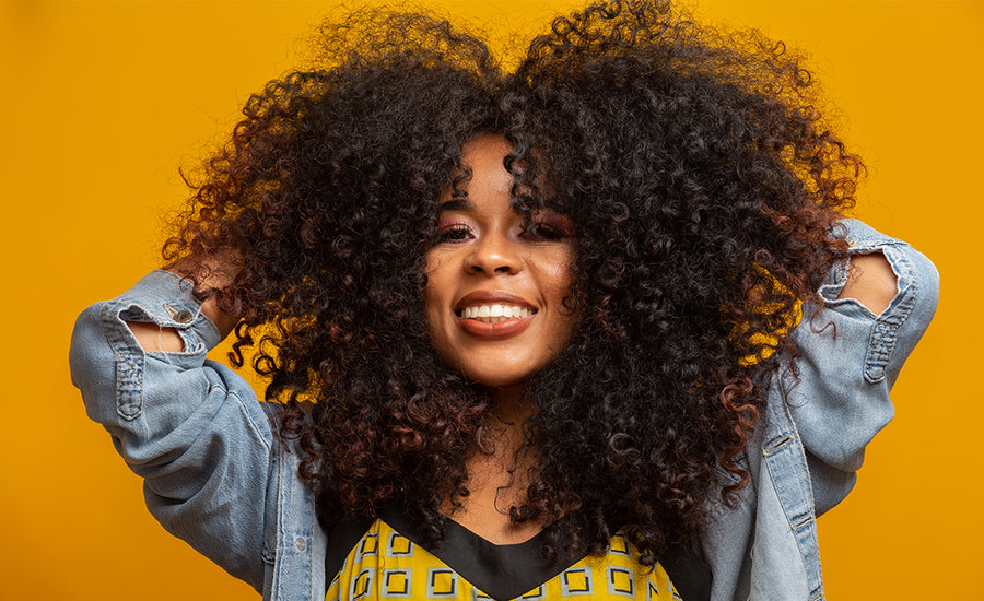 Beauty portrait of african american woman with afro hairstyle and glamour makeup. Brazilian woman. Mixed race. Curly hair. Hair style. Yellow background.