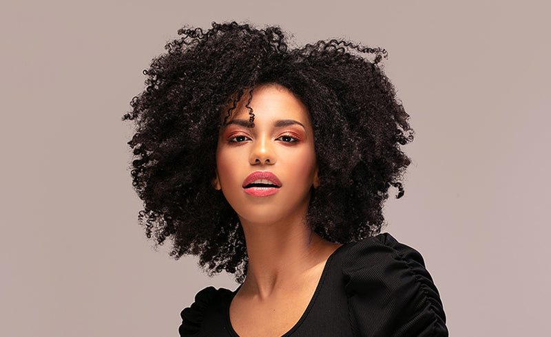 Beautiful african american woman looking at camera with amazing natural hair conditioned by Shea Butter. 
