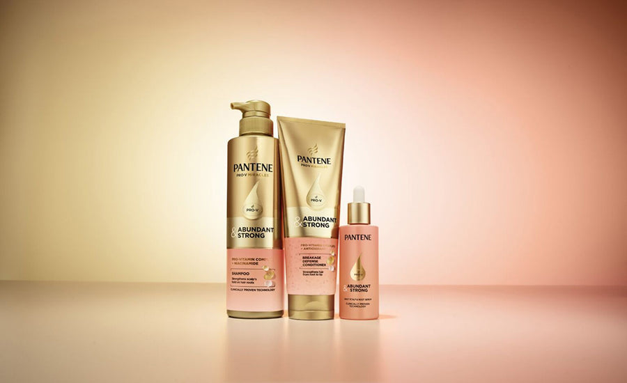 Products of Pantene Abundant & Strong Collection which has clinically proven hair loss treatment technology in front of a yellow and pink background.